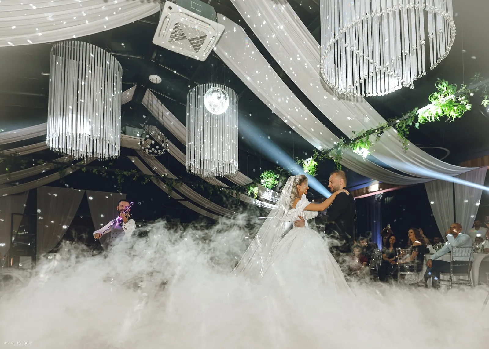 First dance under chandeliers in a cloud of low fog at a wedding reception