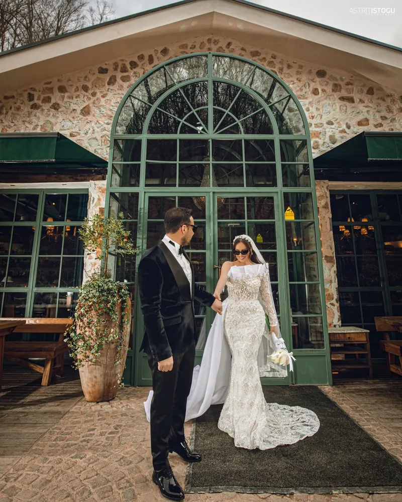 Groom leading the bride out of a stone glasshouse with arched green doors