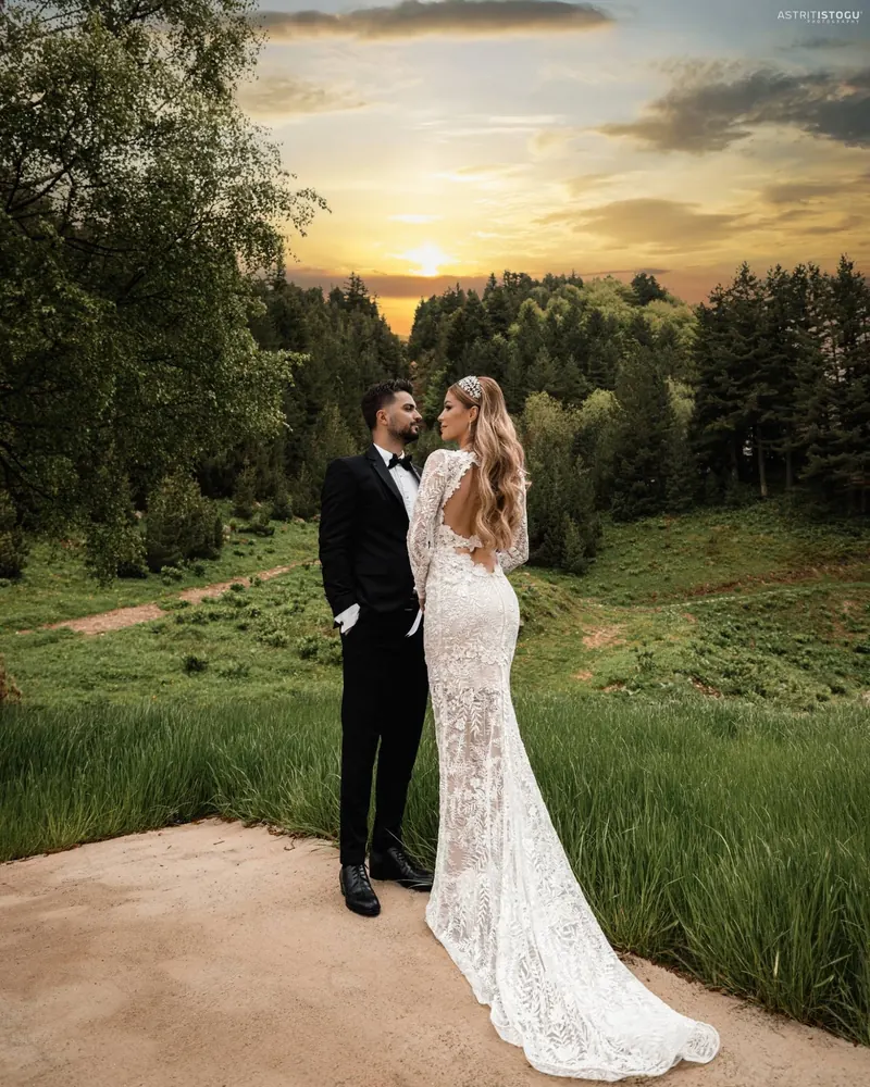 Bride and groom in a green meadow under a golden dusk sky